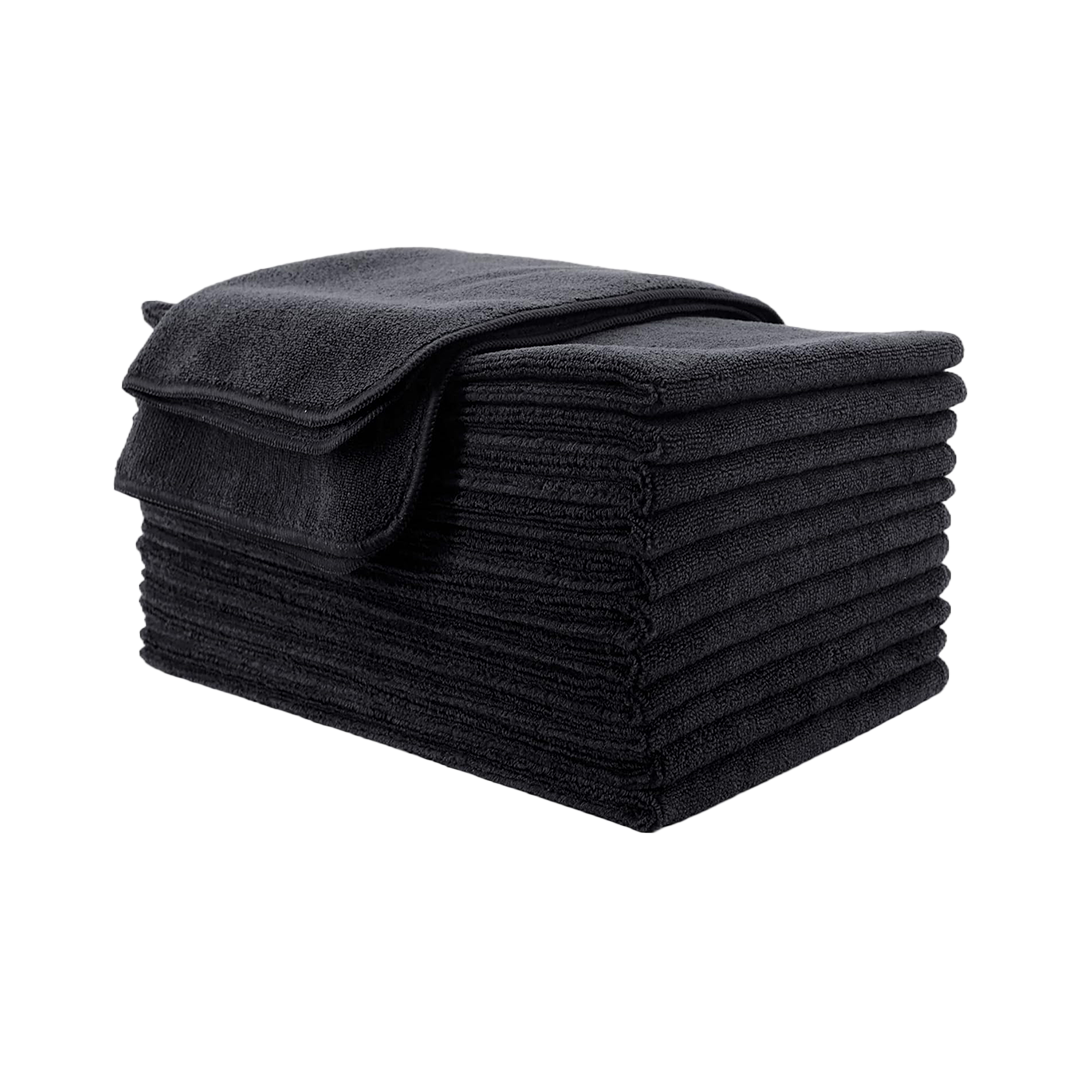 Stack of black folded towels with one rolled towel on top.